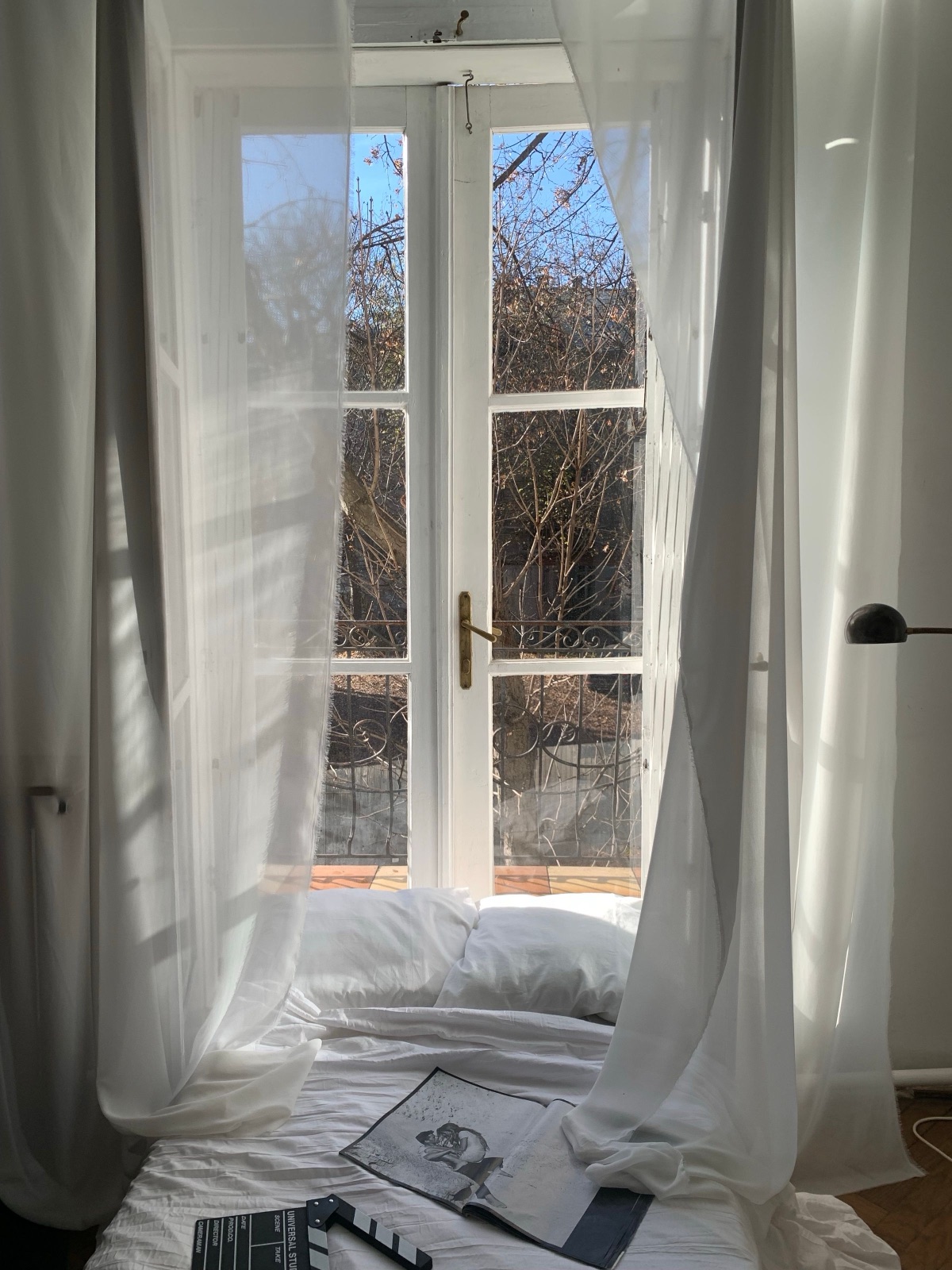 A sunlit bedroom with tall windows and soft curtains