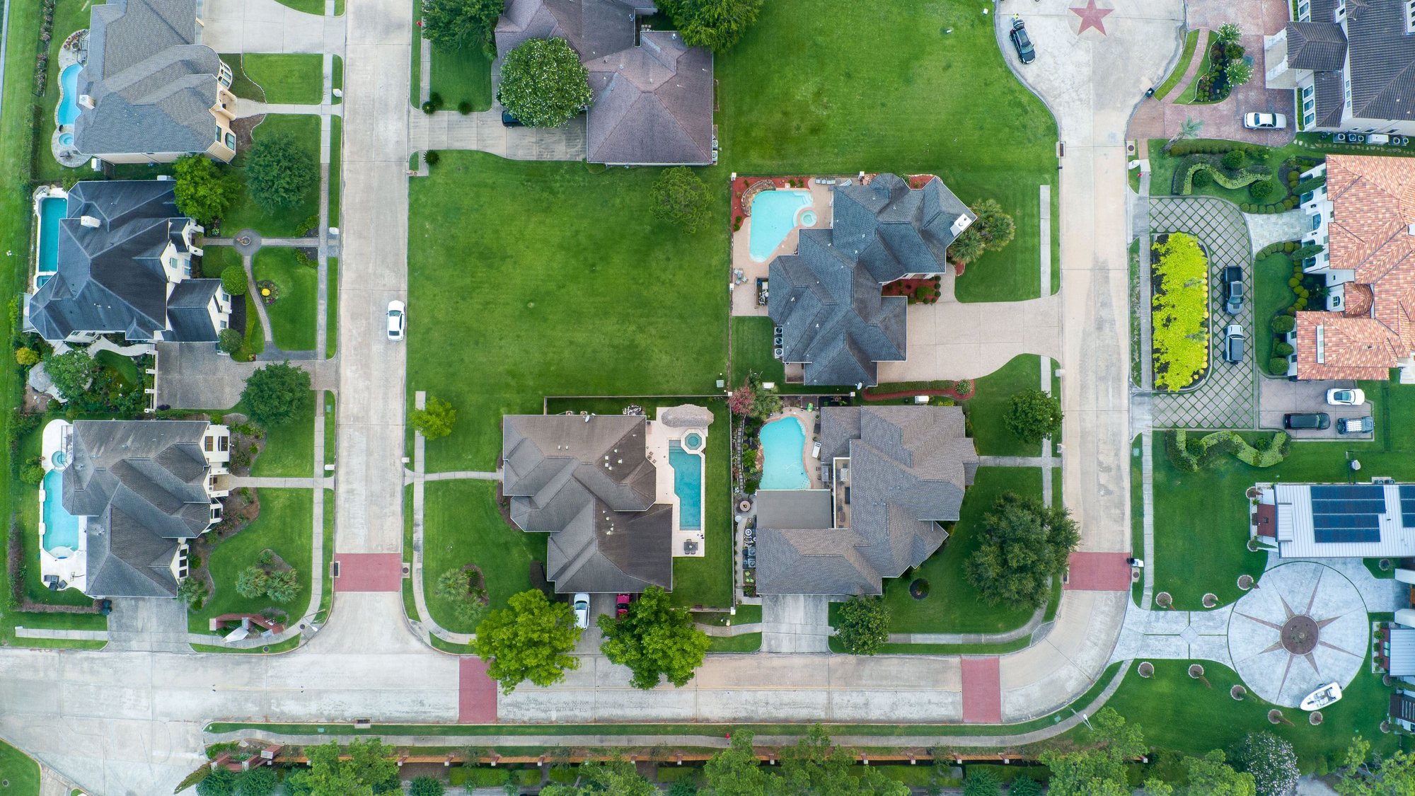 A Houston suburb seen straight down from the air, detached houses and pools around a cul-de-sac