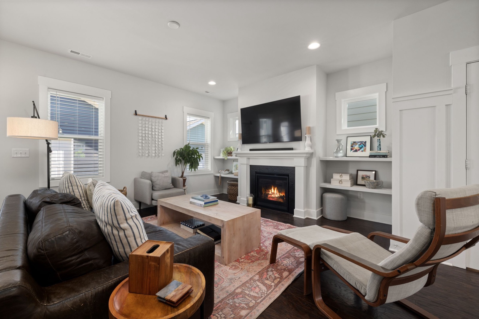 A living room with a lit fireplace, prepared to show